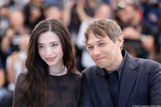 a man and woman posing for a photo in front of a large group of people