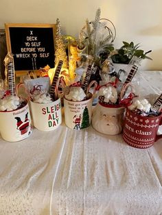 several mugs are sitting on a table with christmas decorations around them and a sign in the background