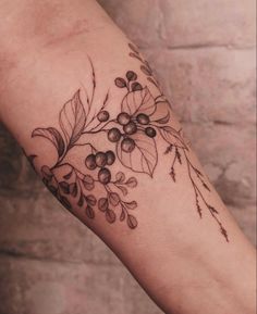 a tattoo with leaves and berries on the arm