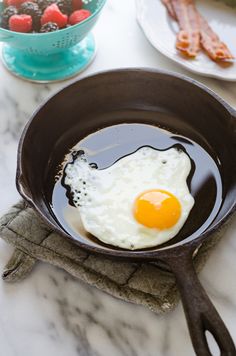 an egg in a frying pan on a marble counter top next to other breakfast foods