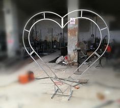 a heart shaped metal object sitting on top of a cement floor next to a building