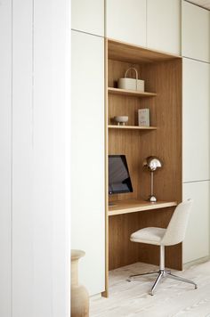 a computer desk with a laptop on top of it next to a white chair and wall