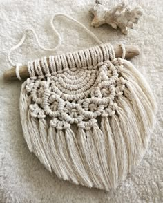 a white crocheted purse sitting on top of a bed next to a wooden object