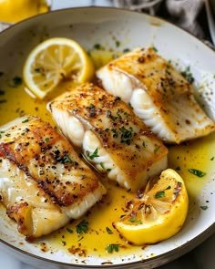 two fish fillets with lemon and parsley on a white plate