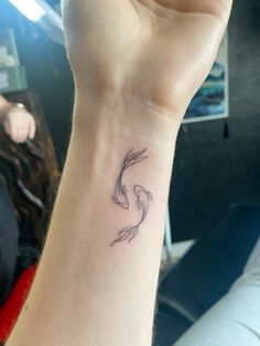 a woman's arm with a tattoo on it that has two fish swimming in the water