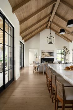 an open kitchen and dining room area with wood floors, white counter tops and wooden ceilinging