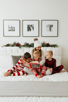 a woman sitting on top of a bed next to two children reading a book together