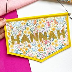 a hand holding a piece of paper with the word hannah on it and flowers all over it