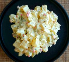 a black plate topped with potato salad on top of a table