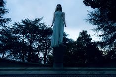 a woman standing on top of a statue next to trees