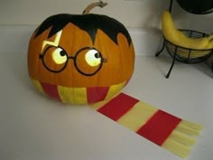 a pumpkin with glasses on it next to a red and yellow striped ribbon in the shape of a jack - o - lantern