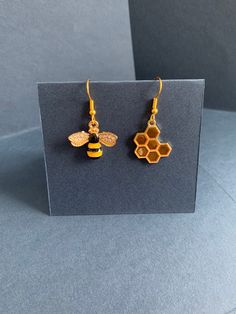 a pair of earrings with honeycombs hanging from the ear hooks on top of a card