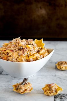 a white bowl filled with food on top of a marble counter next to crackers