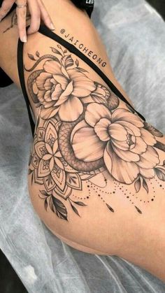 a woman's thigh with flowers on it and an arrow tattoo in the middle