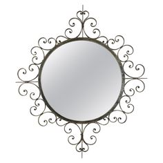 a round metal mirror hanging from the side of a wall with an intricate design on it