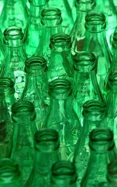 many green glass bottles are stacked together