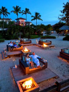 people sitting on couches with fire pit in the middle of them at night time