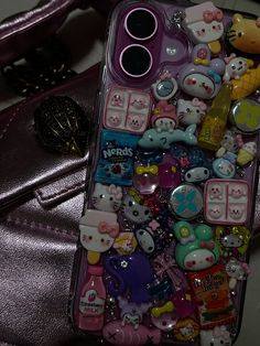 an iphone case with hello kitty stickers on the front and back cover, sitting next to a purse