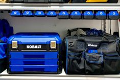 blue toolboxes and black work bags are on display in a storage area with other tools