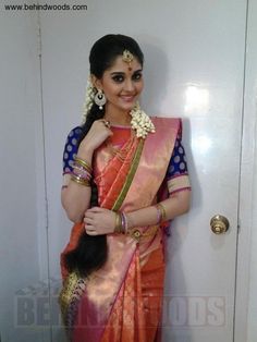 a woman in an orange and blue sari posing for the camera with her hair pulled back