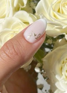 a woman's hand with white manies and flowers in the background, showing her nail art