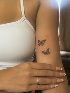 a woman's arm with two small butterflies on the left side of her arm