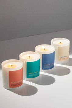 three candles sitting next to each other on top of a white surface with shadows from them