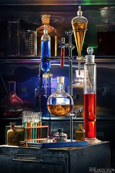 an assortment of different colored liquids and beakles on a table with a black background