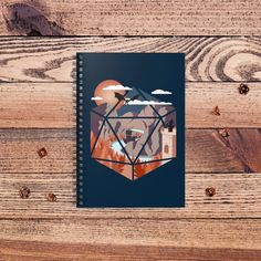 a spiral notebook with an image of a mountain and castle on it, surrounded by wood planks