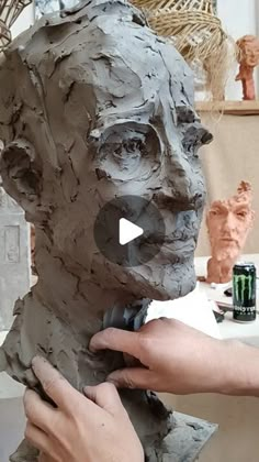 a person is working on a clay busturine that looks like a man's head