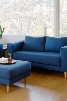 a living room with blue couches and a coffee table in front of a window