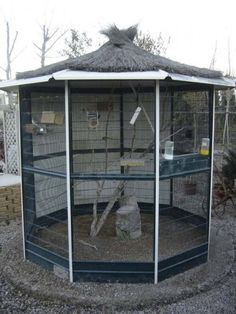 a large bird cage sitting on top of gravel