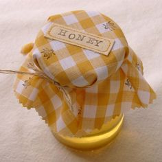 a yellow and white checkered fabric bow on top of a glass jar with some thread in it