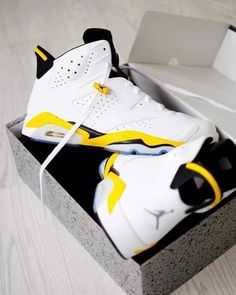 a pair of white and yellow sneakers in a box