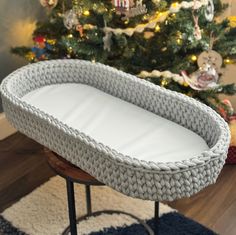 a crocheted bassinet sitting on top of a table next to a christmas tree