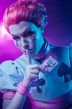 a woman with pink hair and makeup holding a card