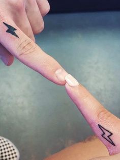 two people with matching tattoos touching each other's fingers and pointing at the same direction