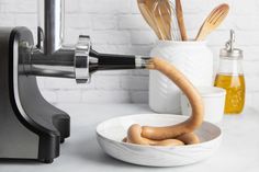 a white bowl filled with wooden utensils on top of a counter next to a blender