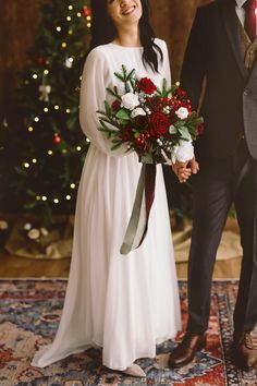 a bride and groom holding hands in front of a christmas tree