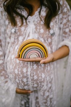 a pregnant woman holding several plates in her hands