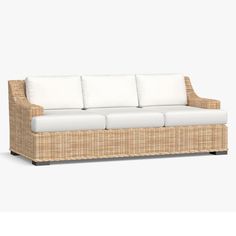 a wicker couch with white cushions