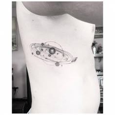 a black and white photo of a saturn tattoo on the back of a woman's stomach