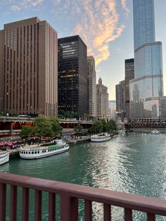 boats are parked along the river in front of tall buildings and skyscrapers at sunset