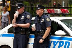 two police officers standing next to each other in front of a cop car and talking