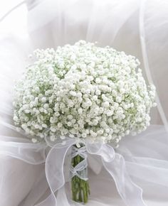 a bouquet of baby's breath sits on a white cloth with a ribbon around it