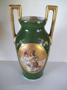 a green vase with gold trimmings on the bottom and sides, depicting two children