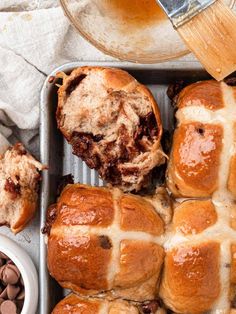 hot cross buns in a baking pan with chocolate chips and butter on the side