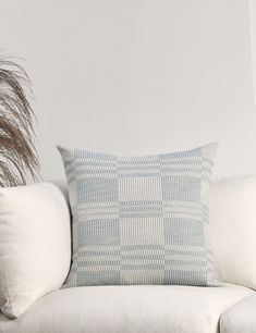 a white couch sitting next to a tall plant