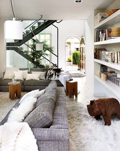 a living room filled with furniture and bookshelves next to a stair case full of books