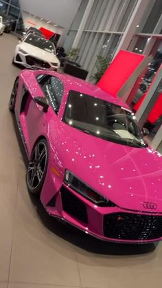 a pink sports car is parked in a showroom